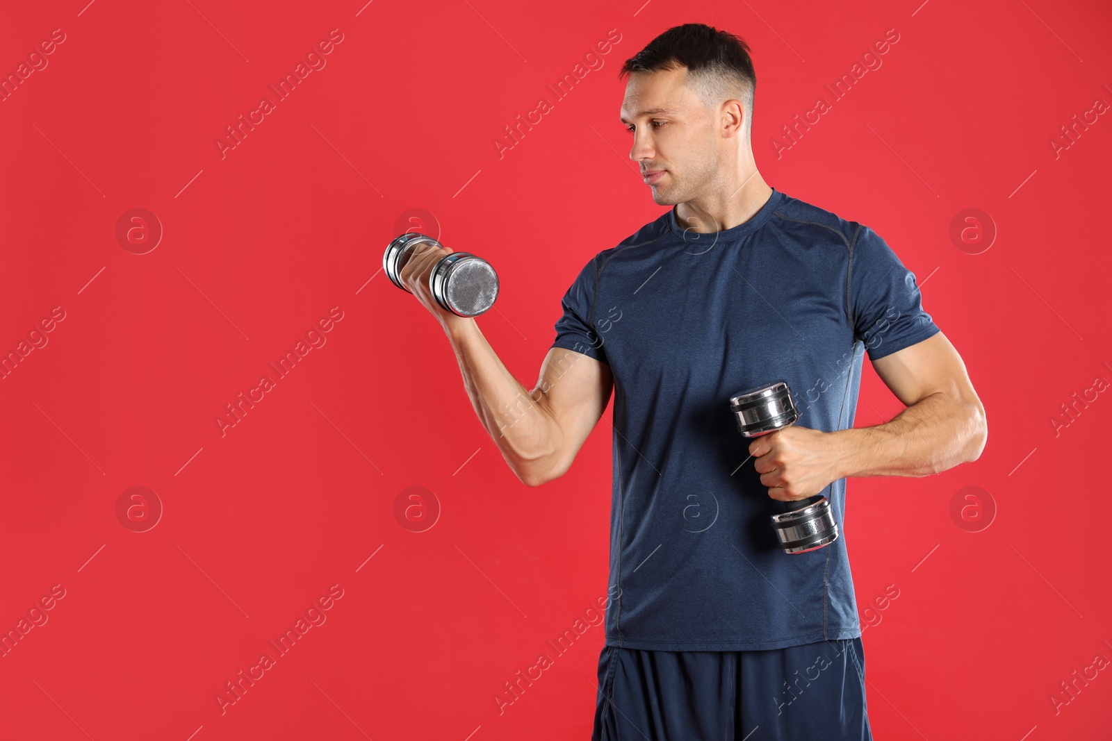 Photo of Man exercising with dumbbells on red background, space for text