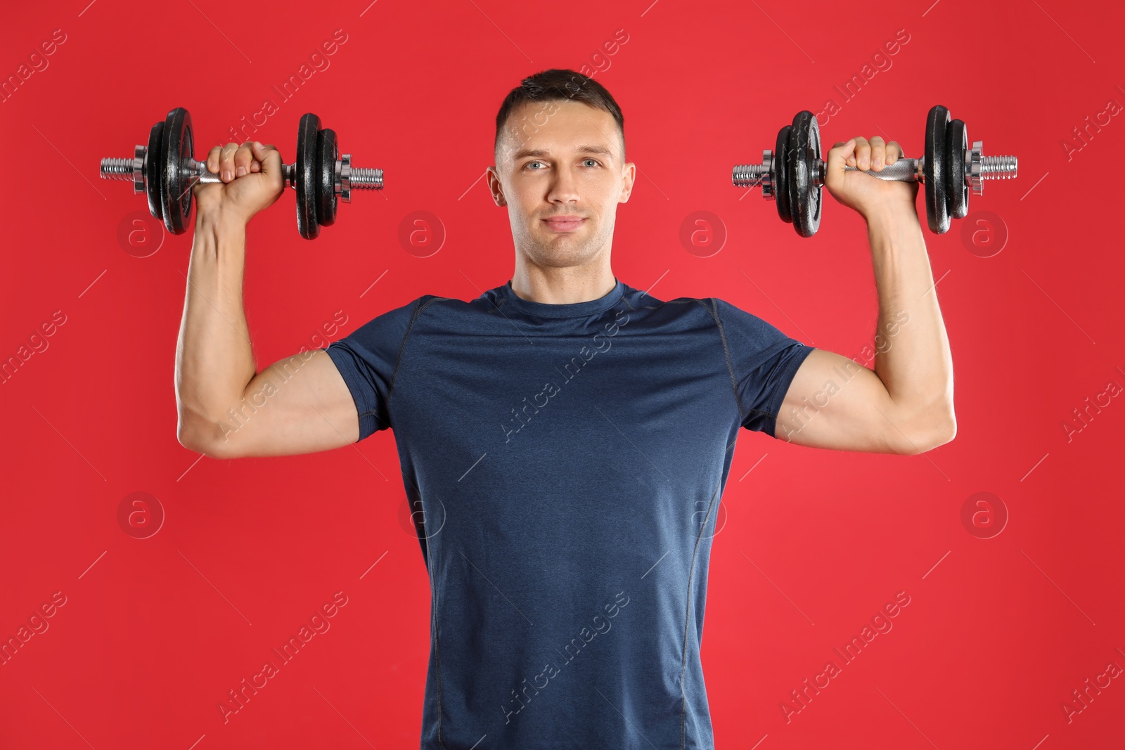 Photo of Man exercising with barbells on red background