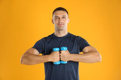 Photo of Man exercising with dumbbells on yellow background