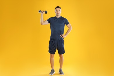 Photo of Man exercising with dumbbell on yellow background