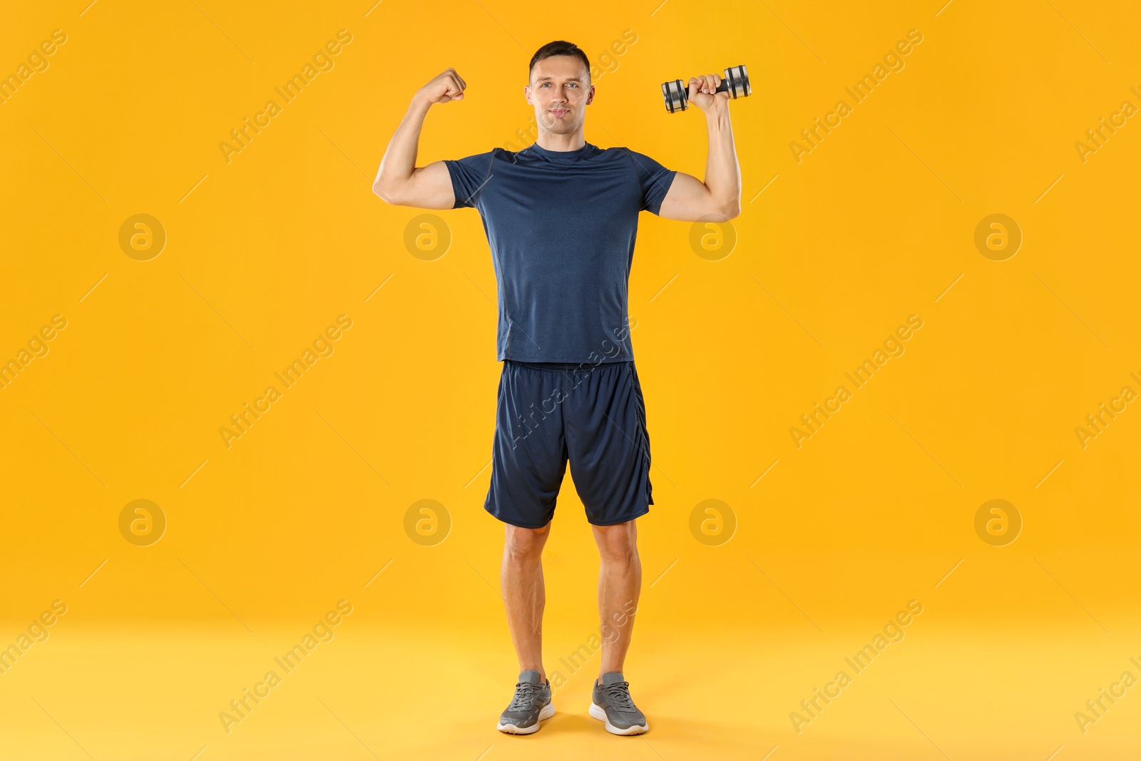 Photo of Man exercising with dumbbell on yellow background