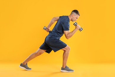 Photo of Man exercising with dumbbells on yellow background