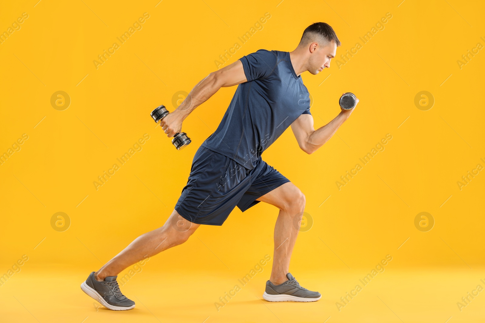 Photo of Man exercising with dumbbells on yellow background