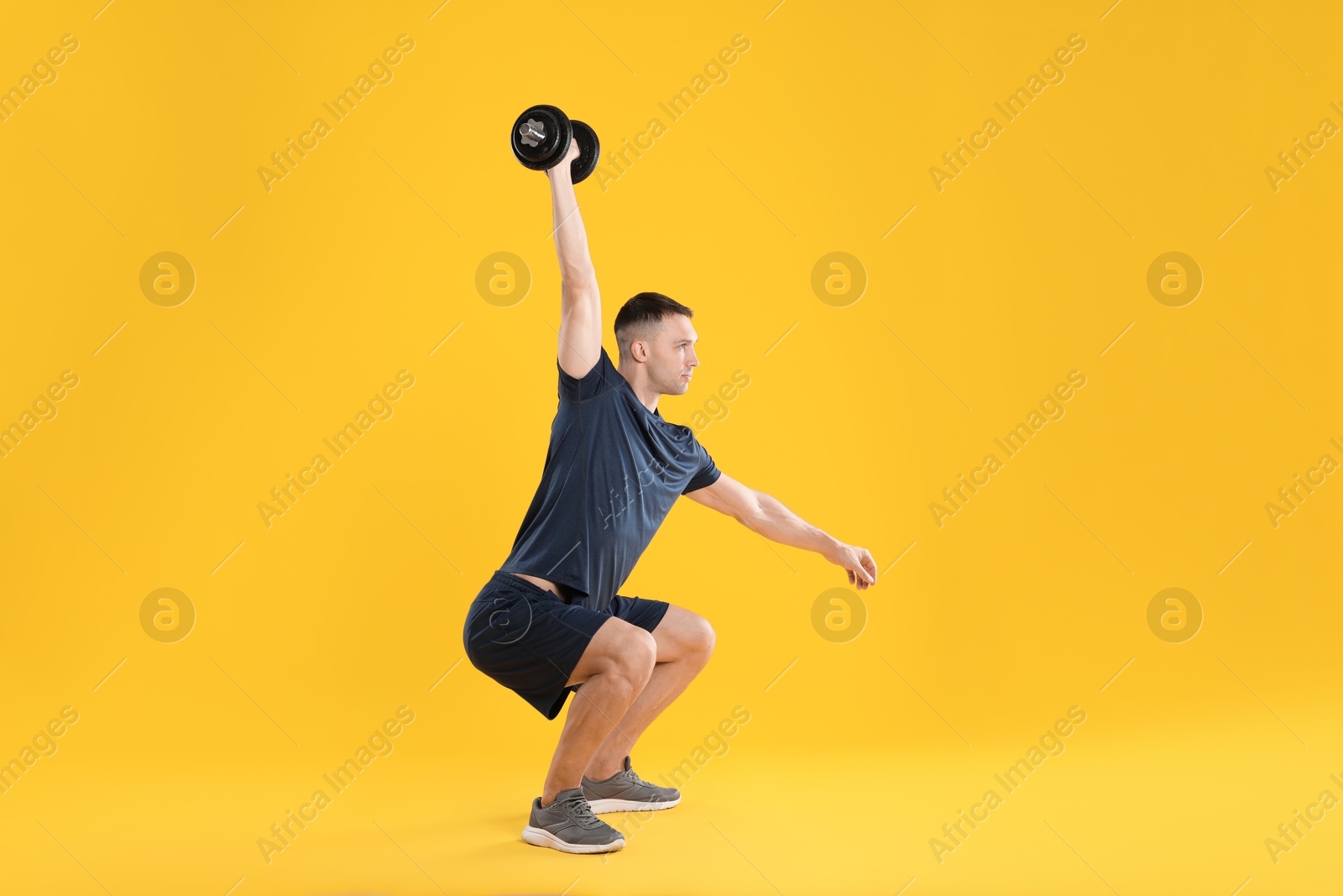 Photo of Man exercising with barbell on yellow background