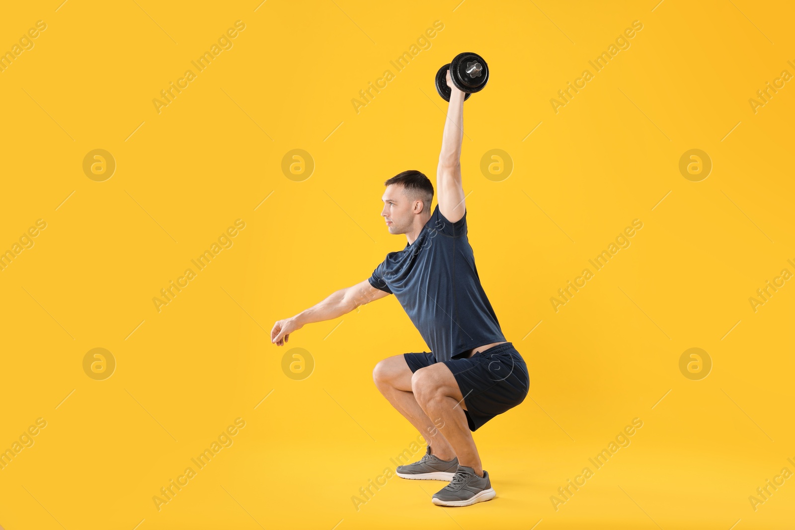 Photo of Man exercising with barbell on yellow background