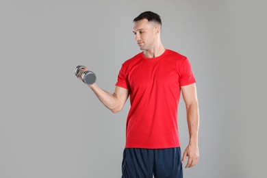 Photo of Man exercising with dumbbell on grey background