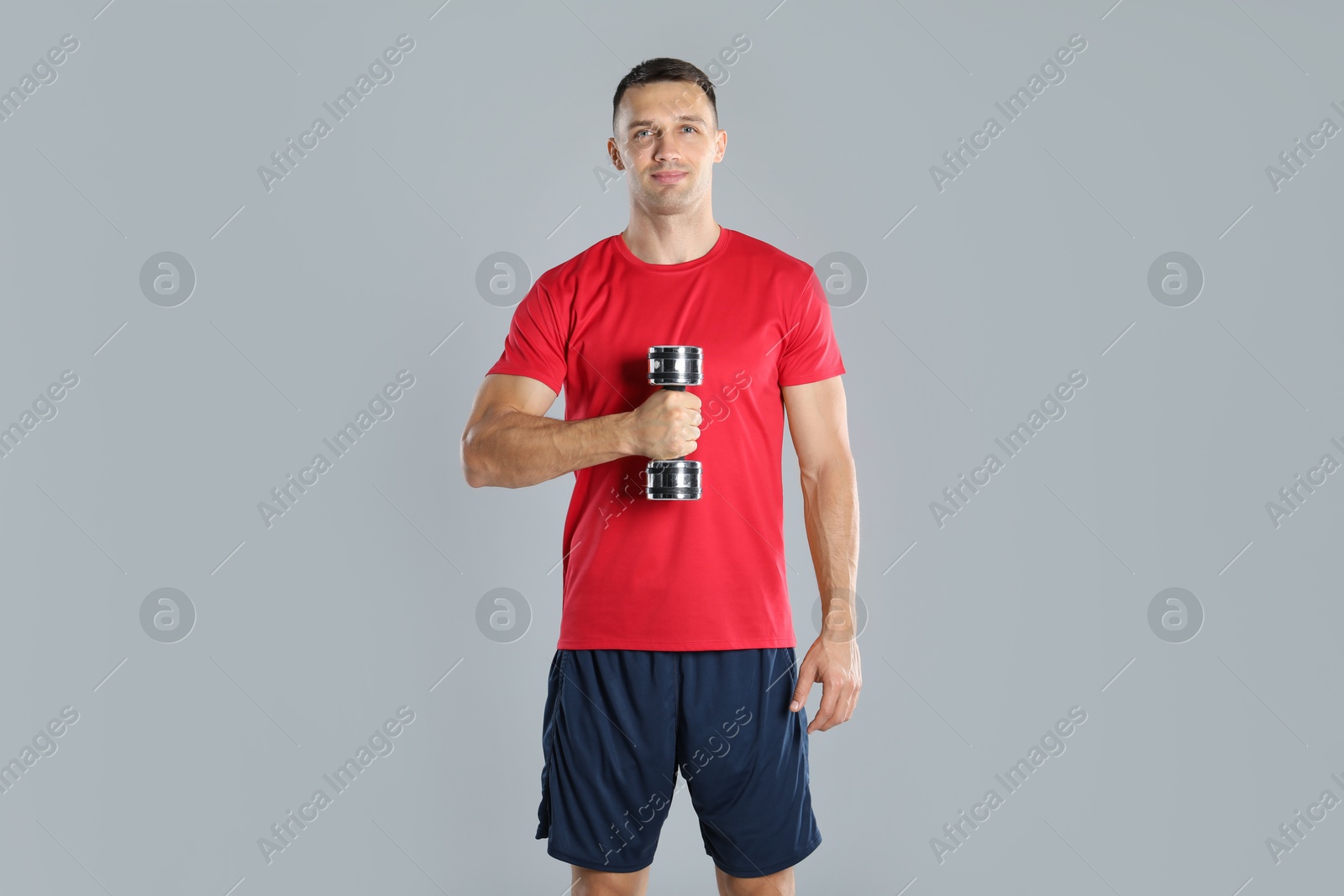 Photo of Man exercising with dumbbell on grey background