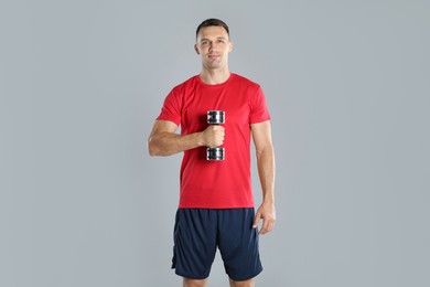 Photo of Man exercising with dumbbell on grey background