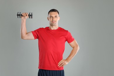 Photo of Man exercising with dumbbell on grey background