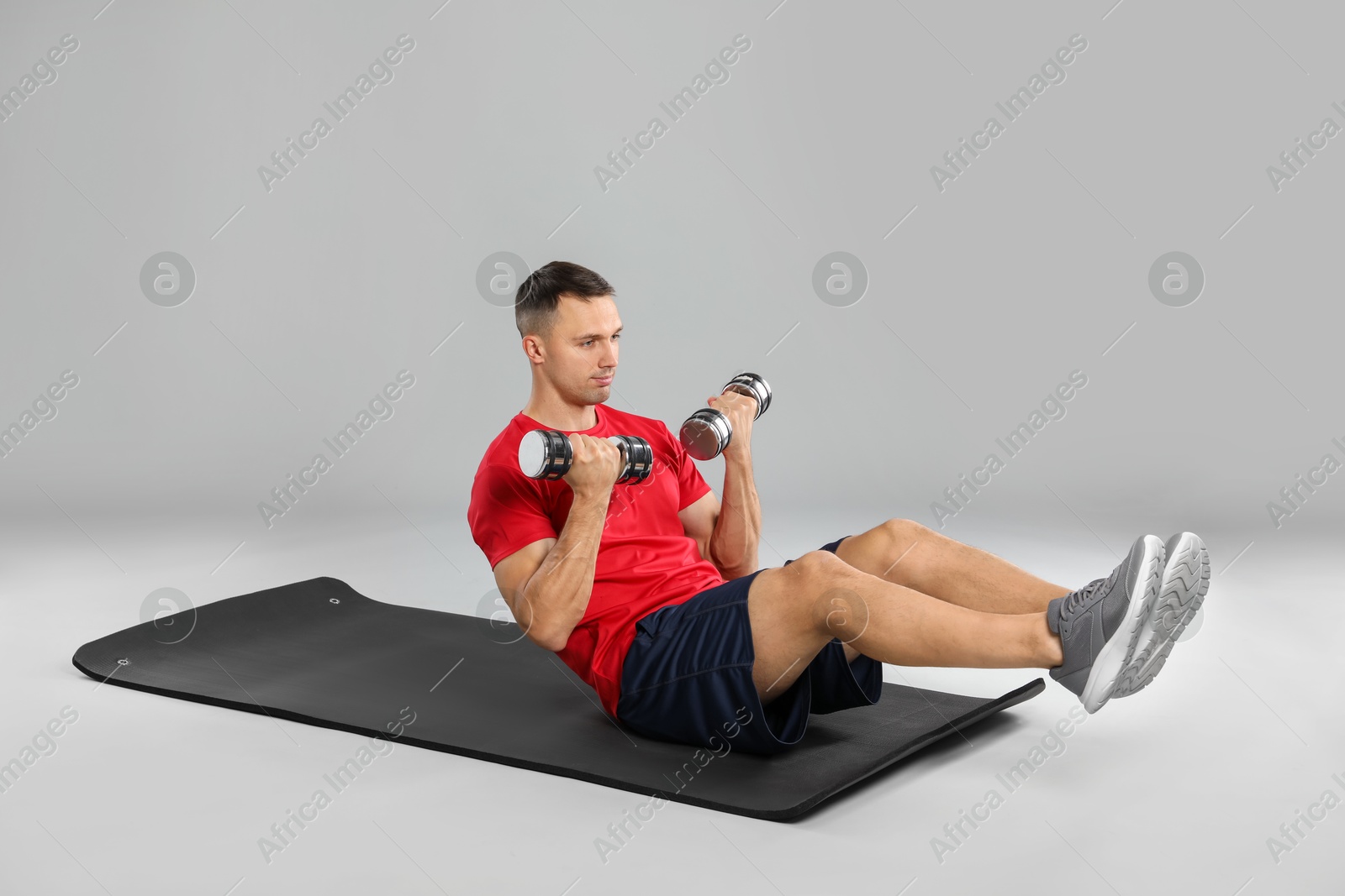 Photo of Man exercising with dumbbells on grey background