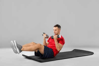 Photo of Man exercising with dumbbells on grey background