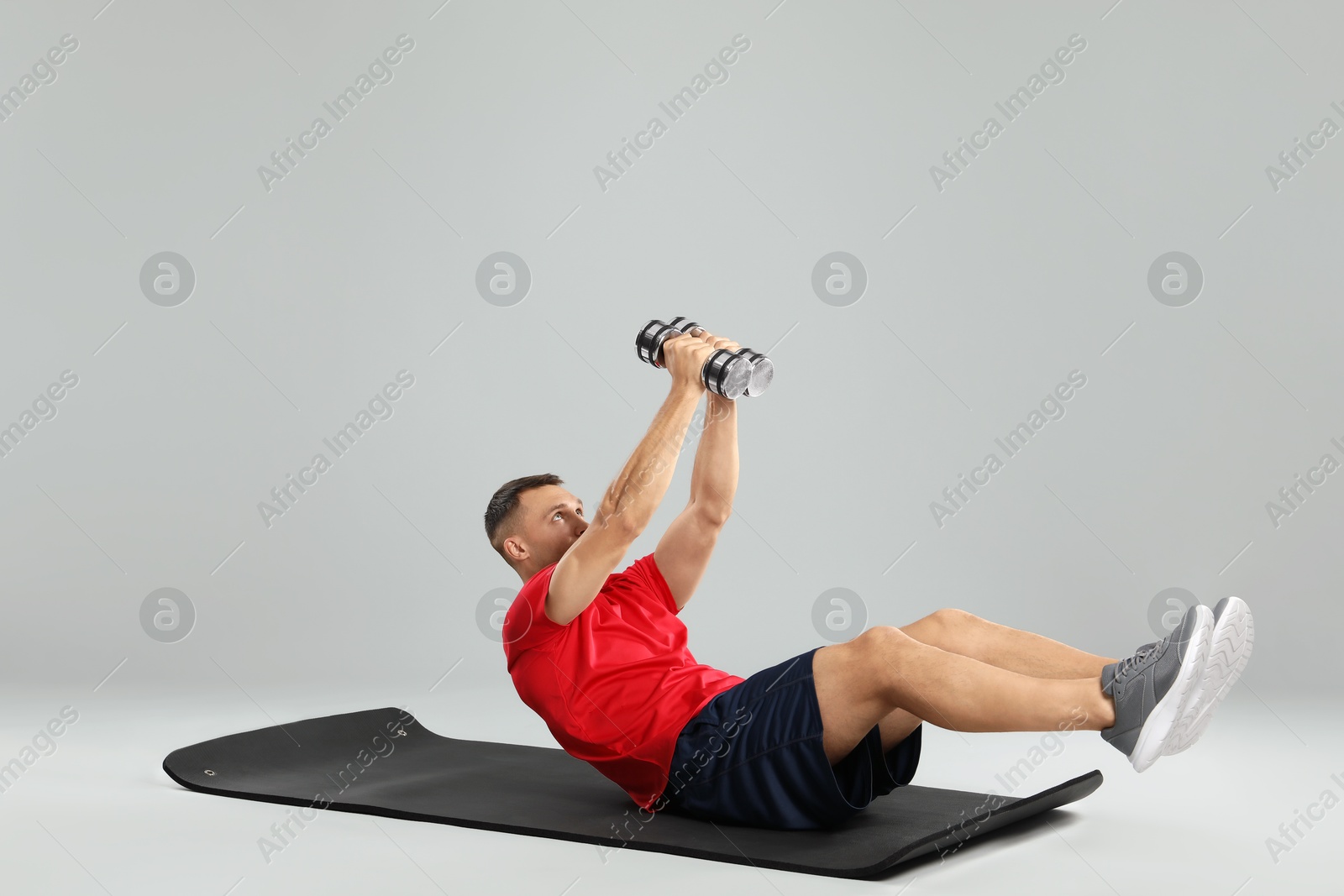 Photo of Man exercising with dumbbells on grey background