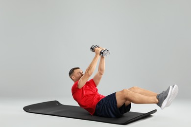 Photo of Man exercising with dumbbells on grey background