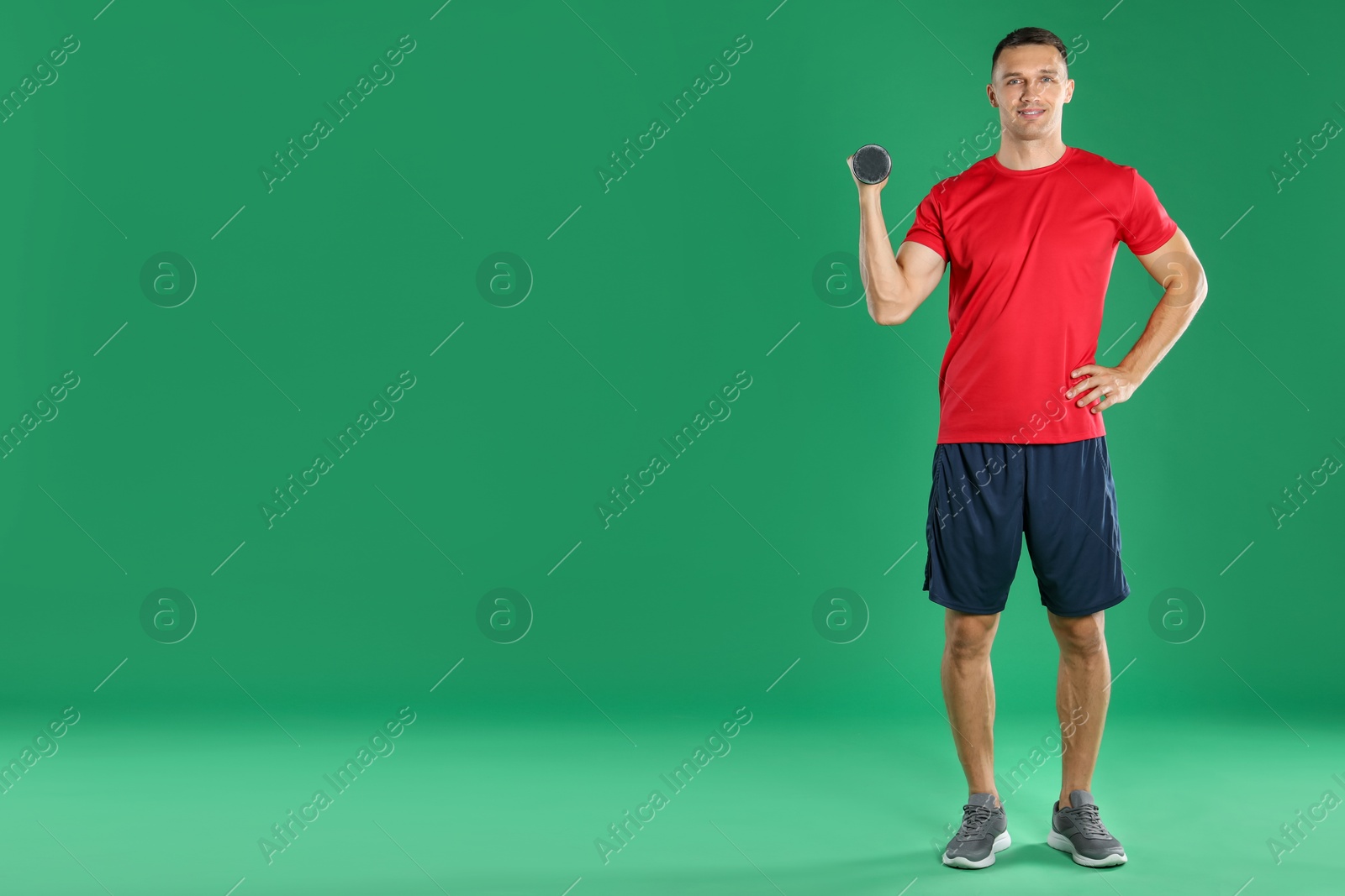 Photo of Man exercising with dumbbell on green background, space for text