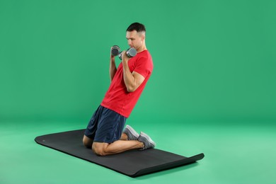 Photo of Man exercising with dumbbells on green background