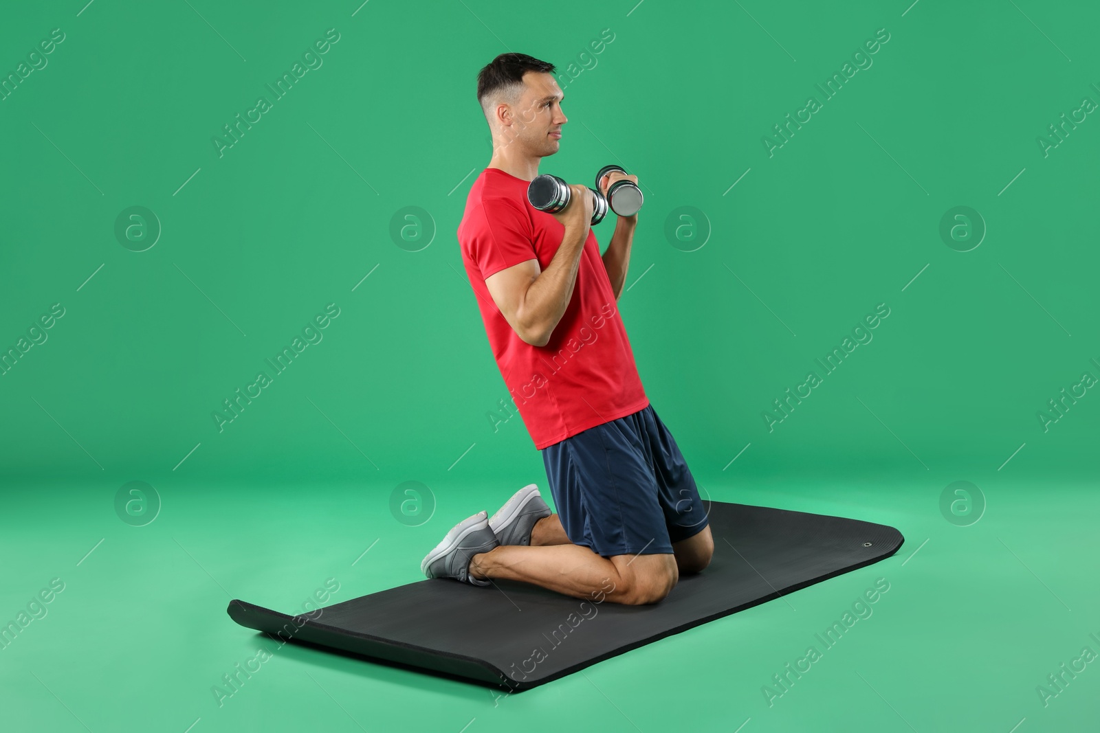 Photo of Man exercising with dumbbells on green background