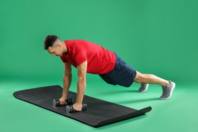 Photo of Man exercising with dumbbells on green background