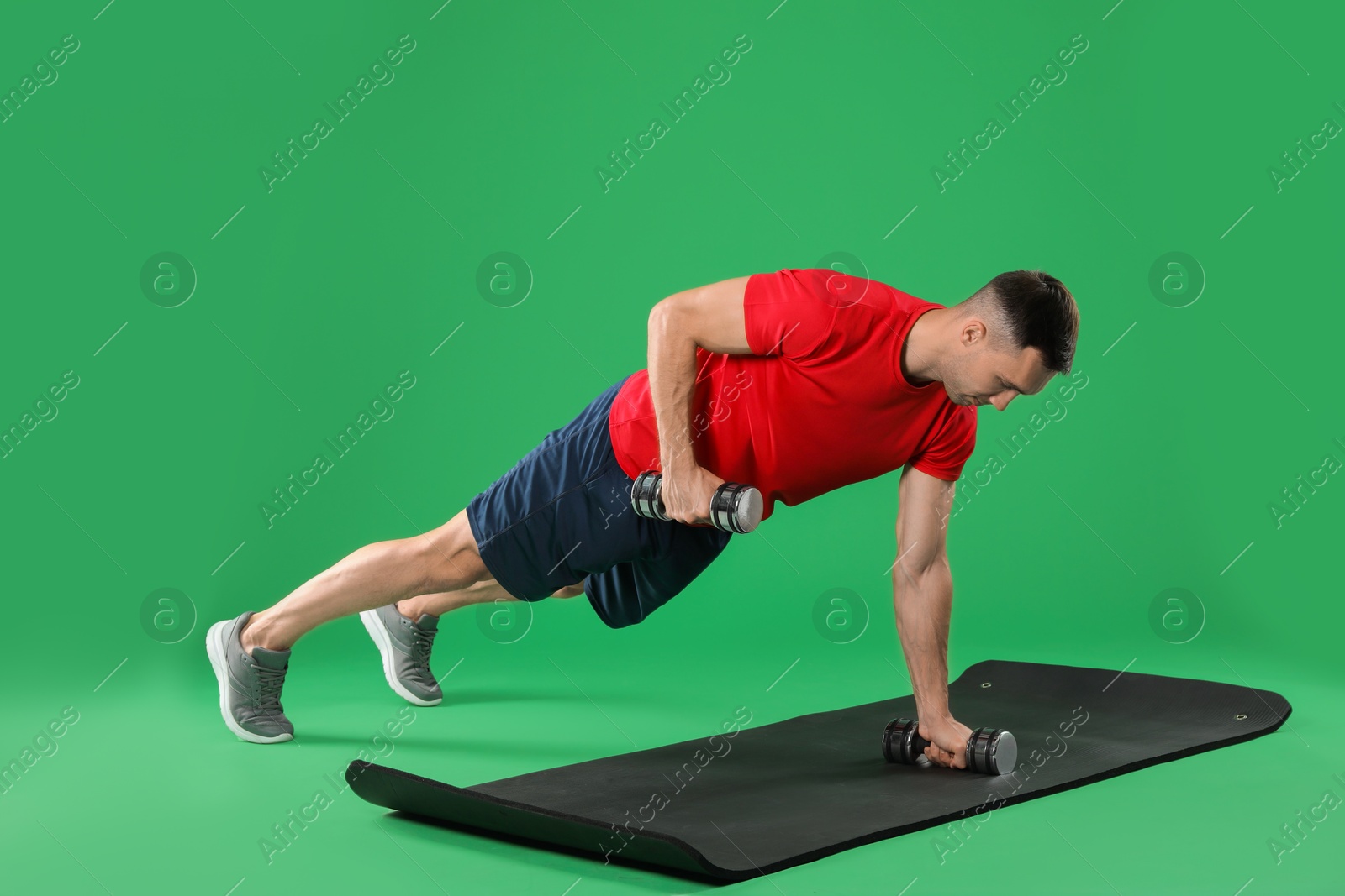 Photo of Man exercising with dumbbells on green background