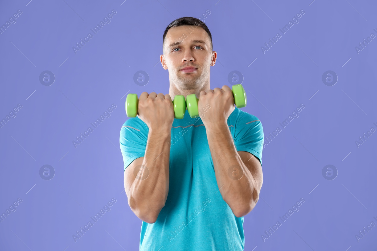 Photo of Man exercising with dumbbells on violet background