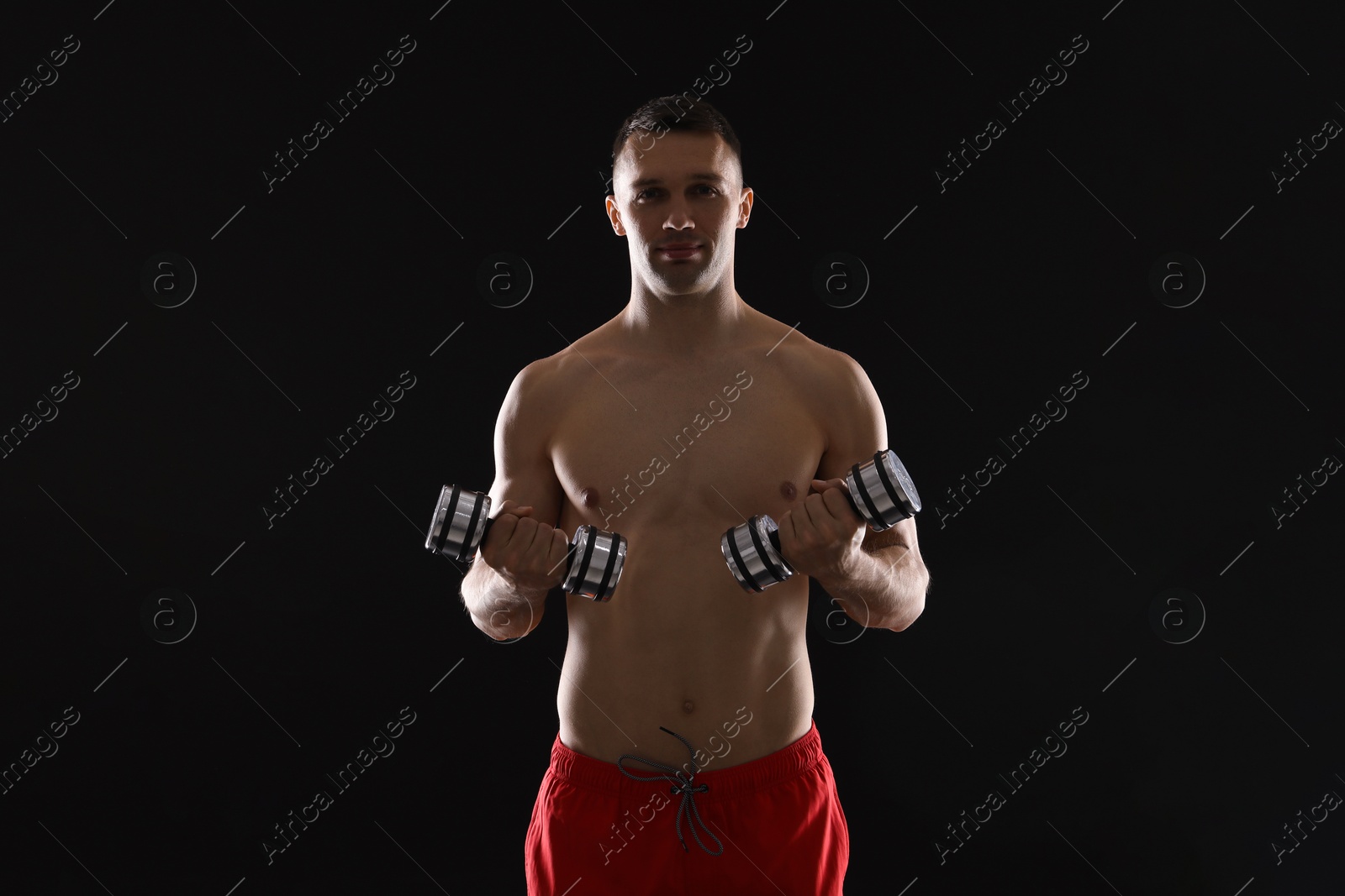 Photo of Man exercising with dumbbells on black background