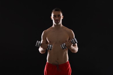 Photo of Man exercising with dumbbells on black background