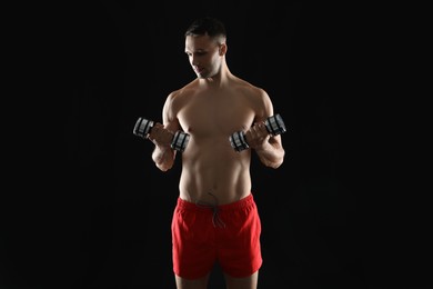 Photo of Man exercising with dumbbells on black background