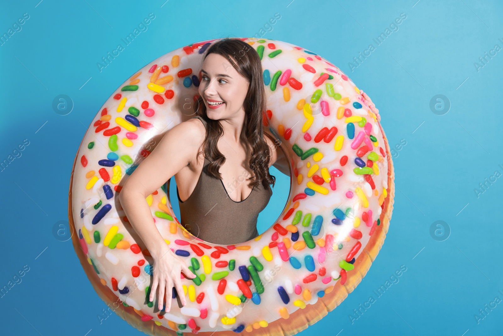 Photo of Beautiful woman in swimsuit with inflatable ring on light blue background