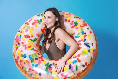 Photo of Beautiful woman in swimsuit with inflatable ring on light blue background