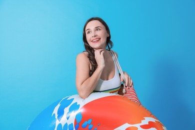 Photo of Beautiful woman in swimsuit with inflatable ring on light blue background