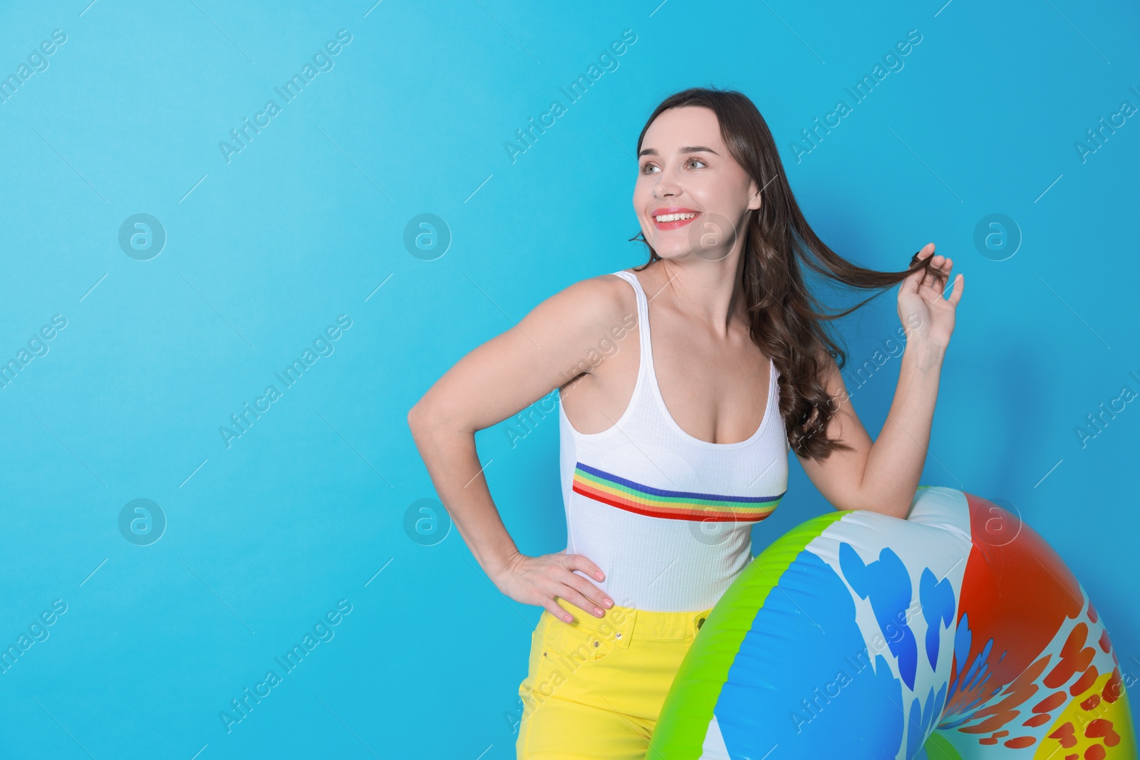 Photo of Beautiful woman in swimsuit with inflatable ring on light blue background. Space for text