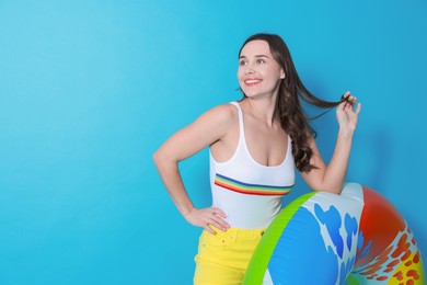 Photo of Beautiful woman in swimsuit with inflatable ring on light blue background. Space for text