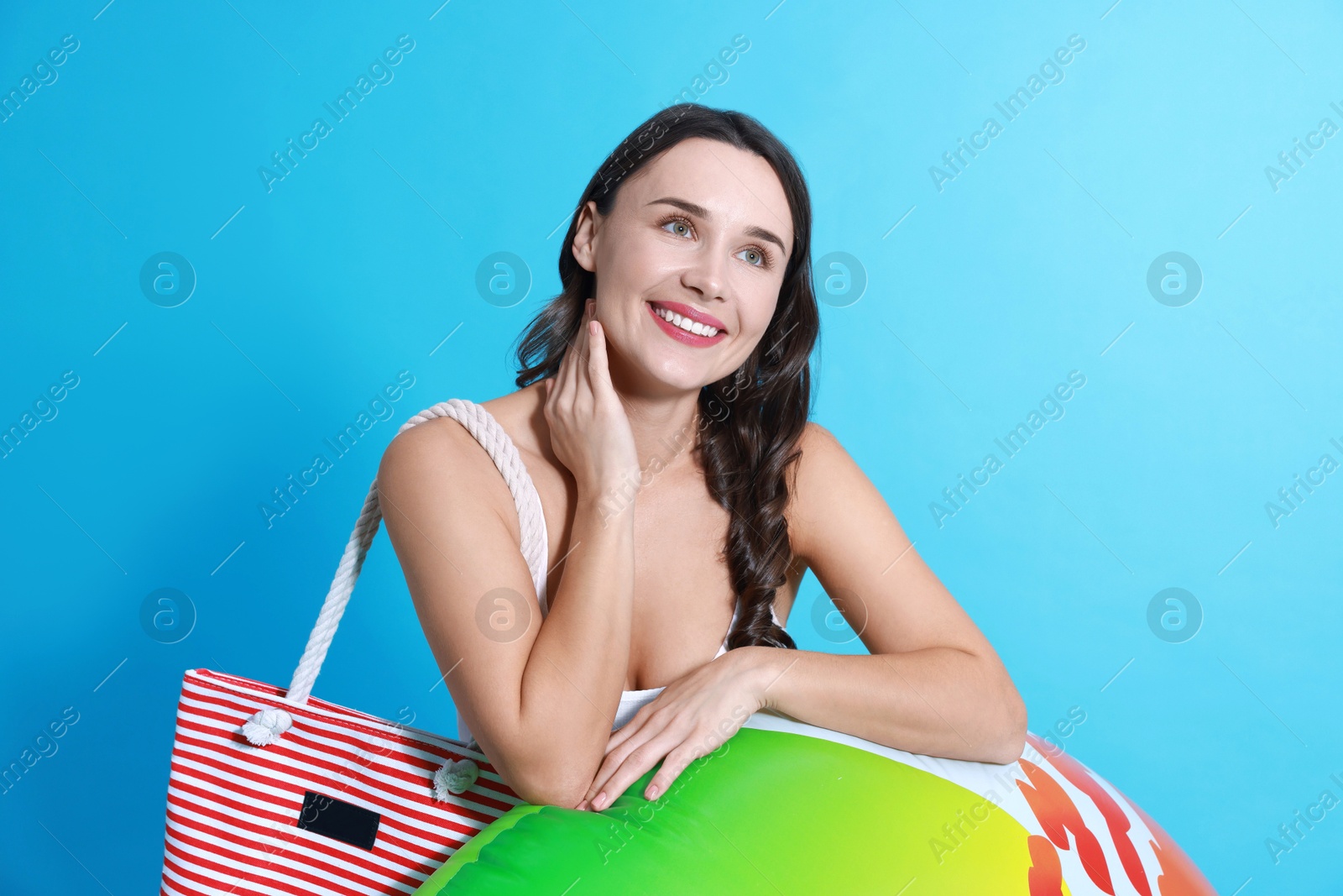 Photo of Beautiful woman in swimsuit with inflatable ring on light blue background