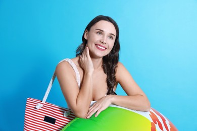 Photo of Beautiful woman in swimsuit with inflatable ring on light blue background