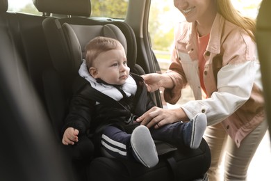 Photo of Smiling mother fastening her baby in car seat, closeup