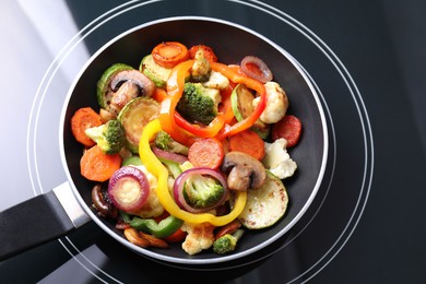 Photo of Frying pan with mix of vegetables and mushrooms on cooktop, above view