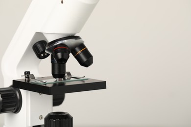 Photo of Science. Microscope with glass slide on light grey background, closeup. Space for text