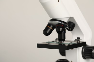 Photo of Science. Microscope with glass slide on light grey background, closeup. Space for text