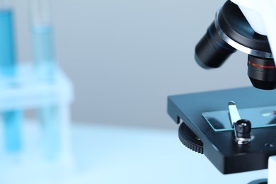 Science. Microscope with glass slide on blurred background, closeup. Space for text