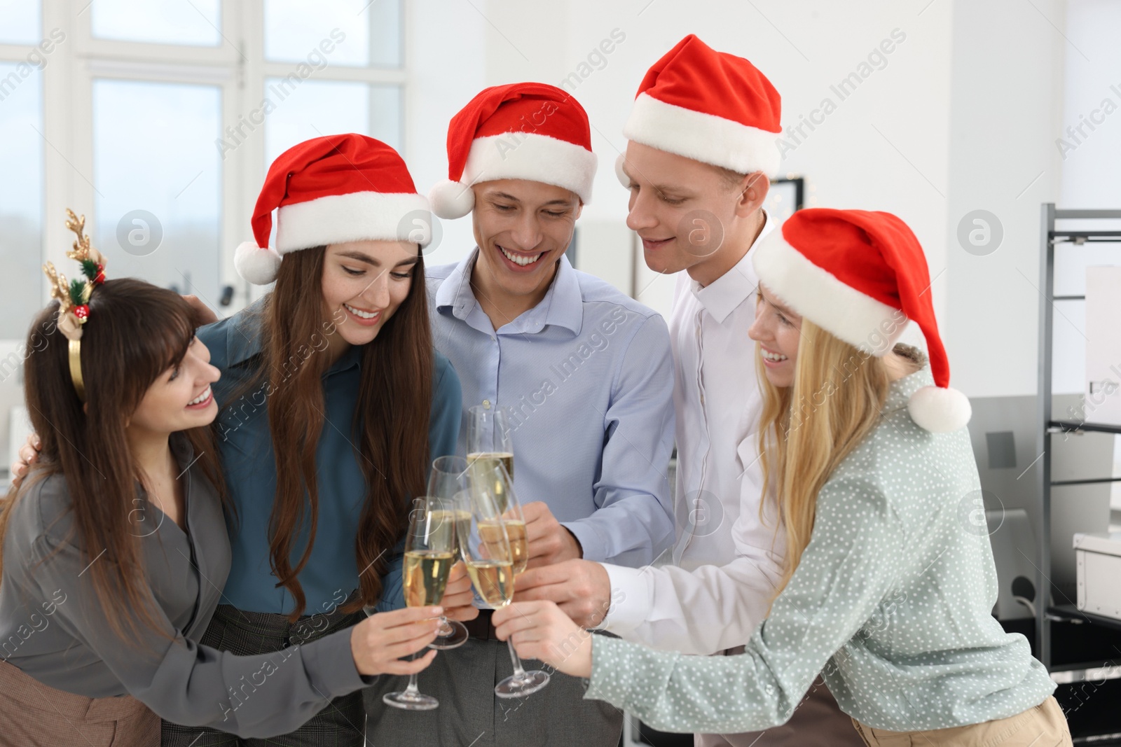 Photo of Happy coworkers clinking glasses of wine during office Christmas party