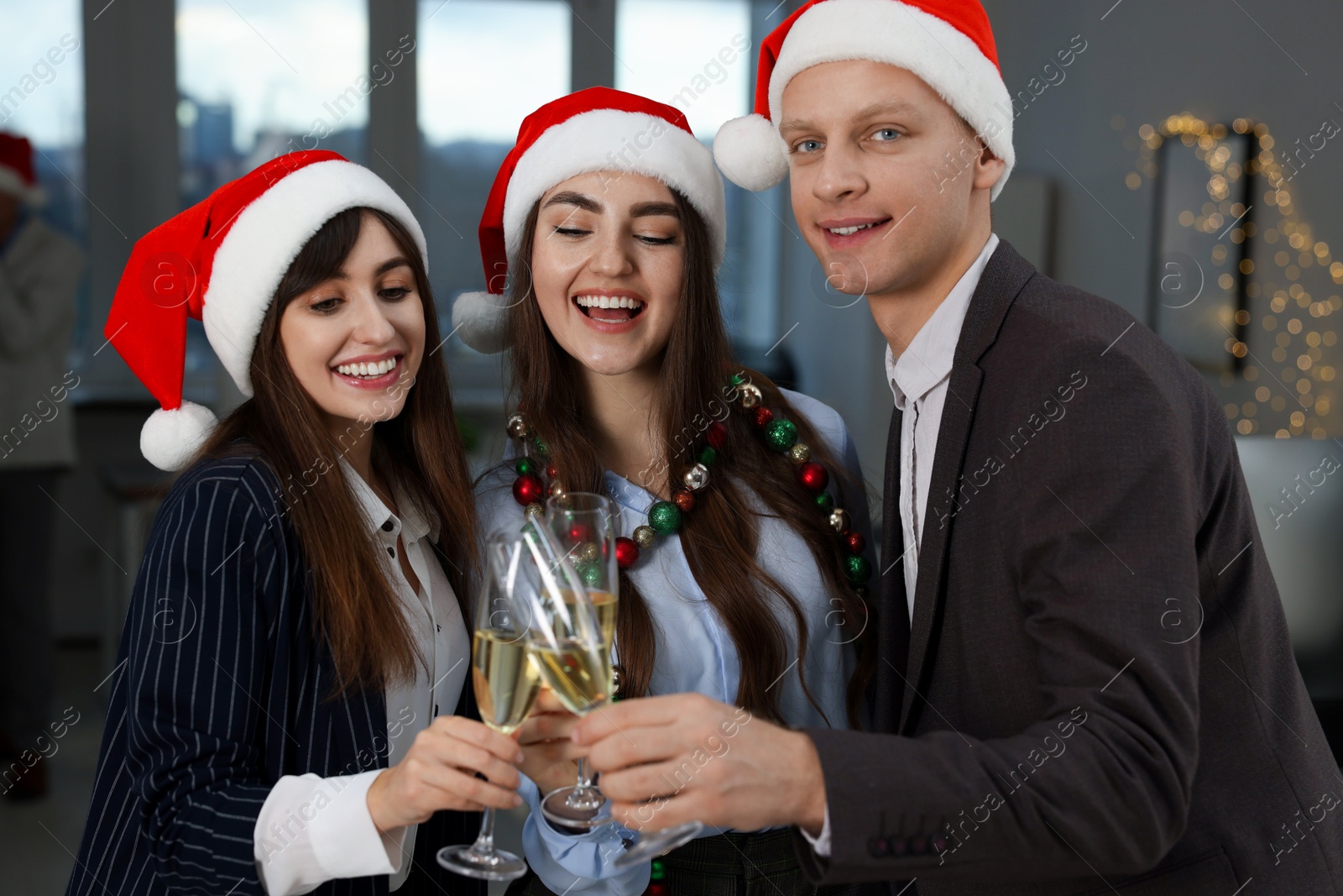 Photo of Happy coworkers clinking glasses of wine during office Christmas party