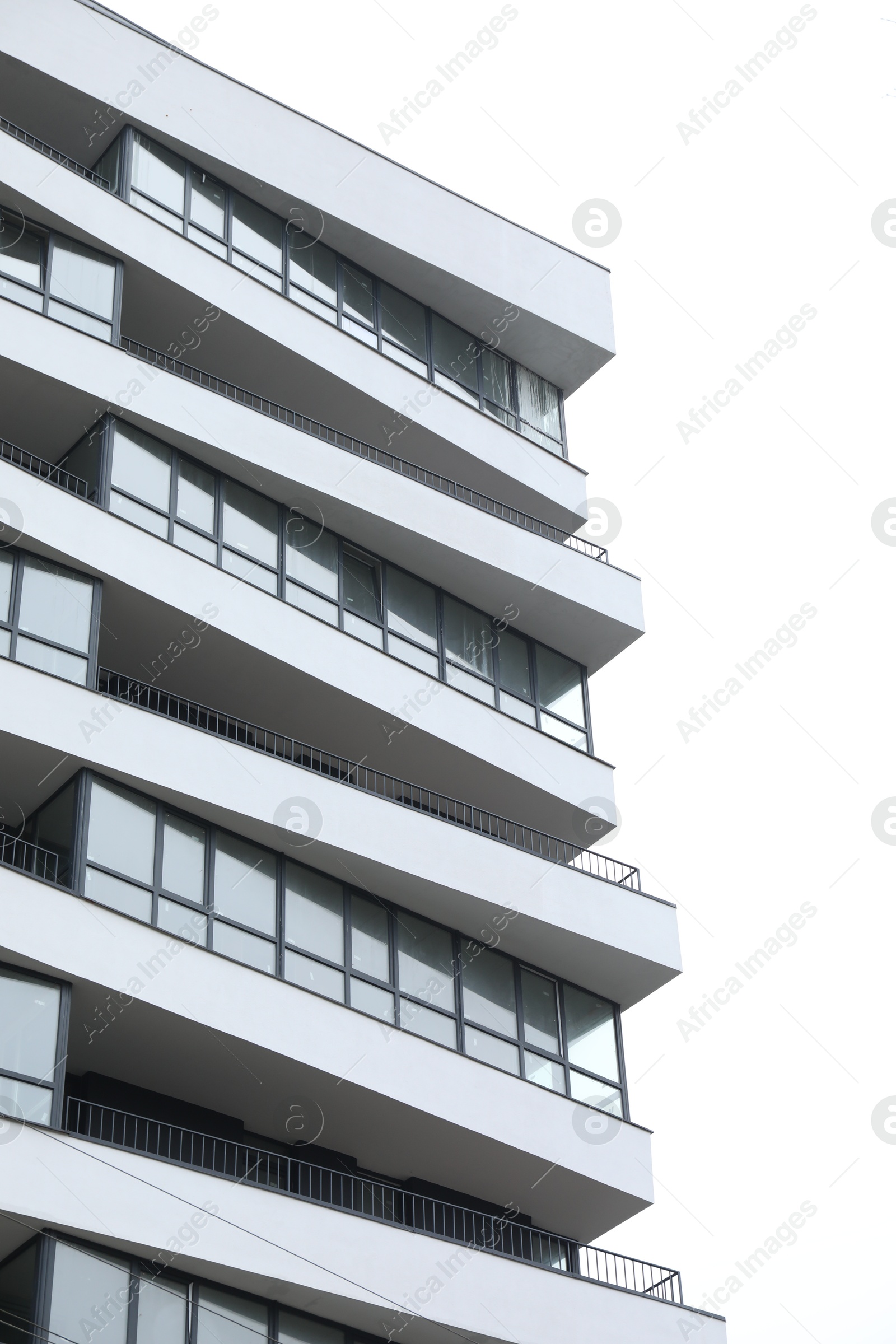 Photo of Modern building with many windows against blue sky, low angle view