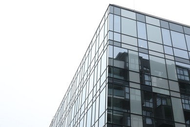 Photo of Modern building with many windows against blue sky, low angle view