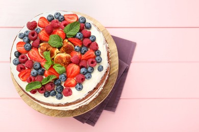 Photo of Delicious chocolate sponge cake with berries on pink wooden table, top view. Space for text