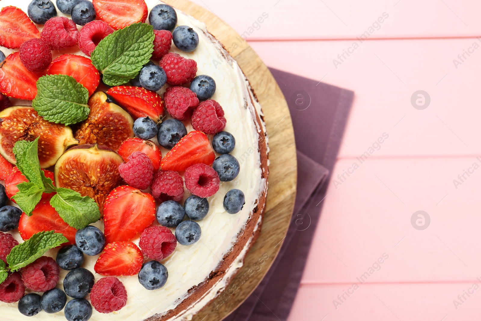 Photo of Delicious chocolate sponge cake with berries on pink wooden table, top view. Space for text