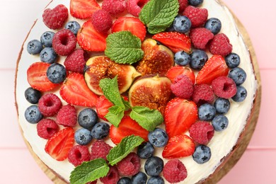 Photo of Delicious chocolate sponge cake with berries on pink table, top view