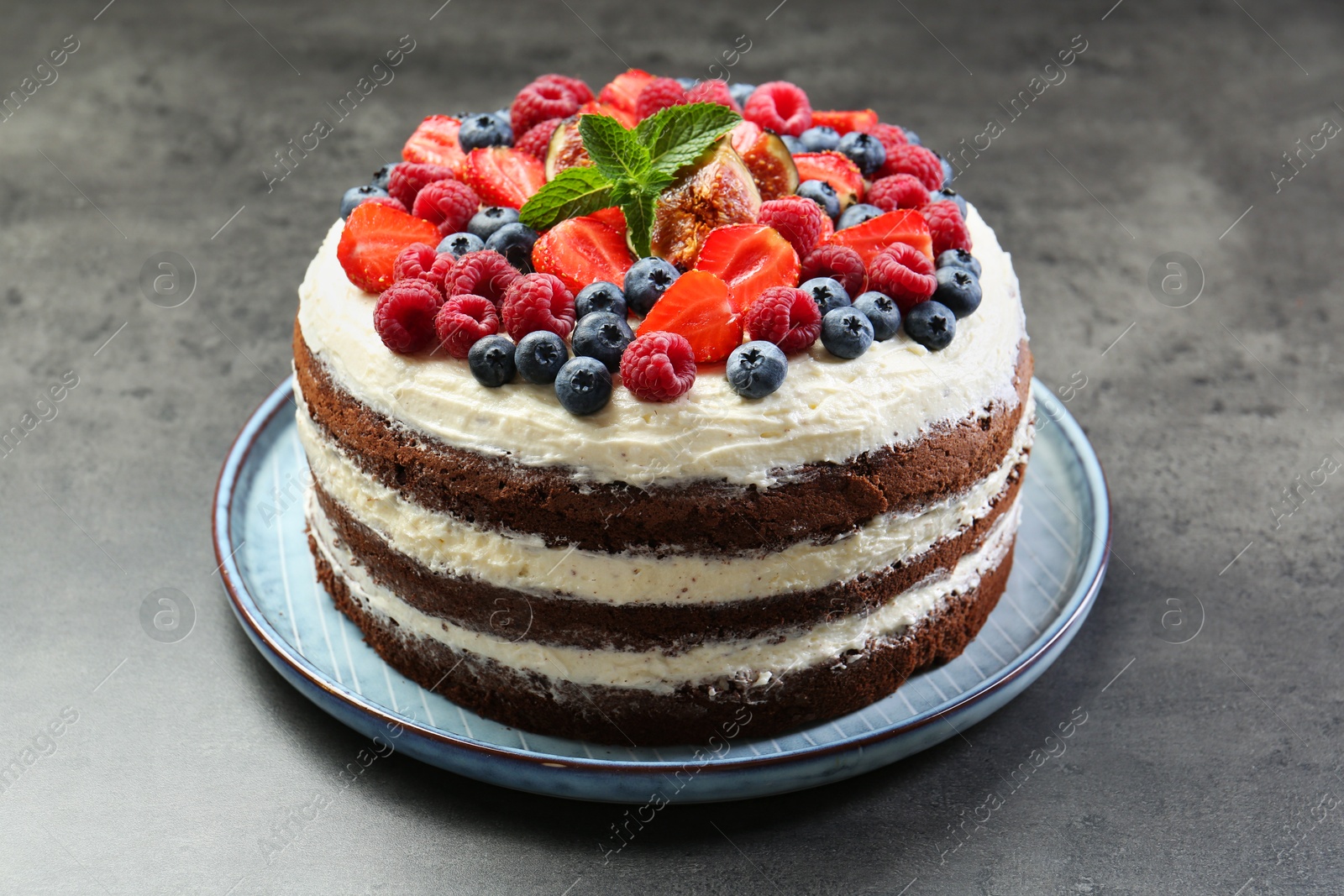 Photo of Delicious chocolate sponge cake with berries on grey table, closeup