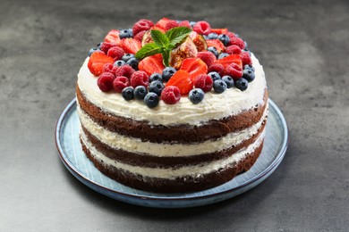 Delicious chocolate sponge cake with berries on grey table, closeup