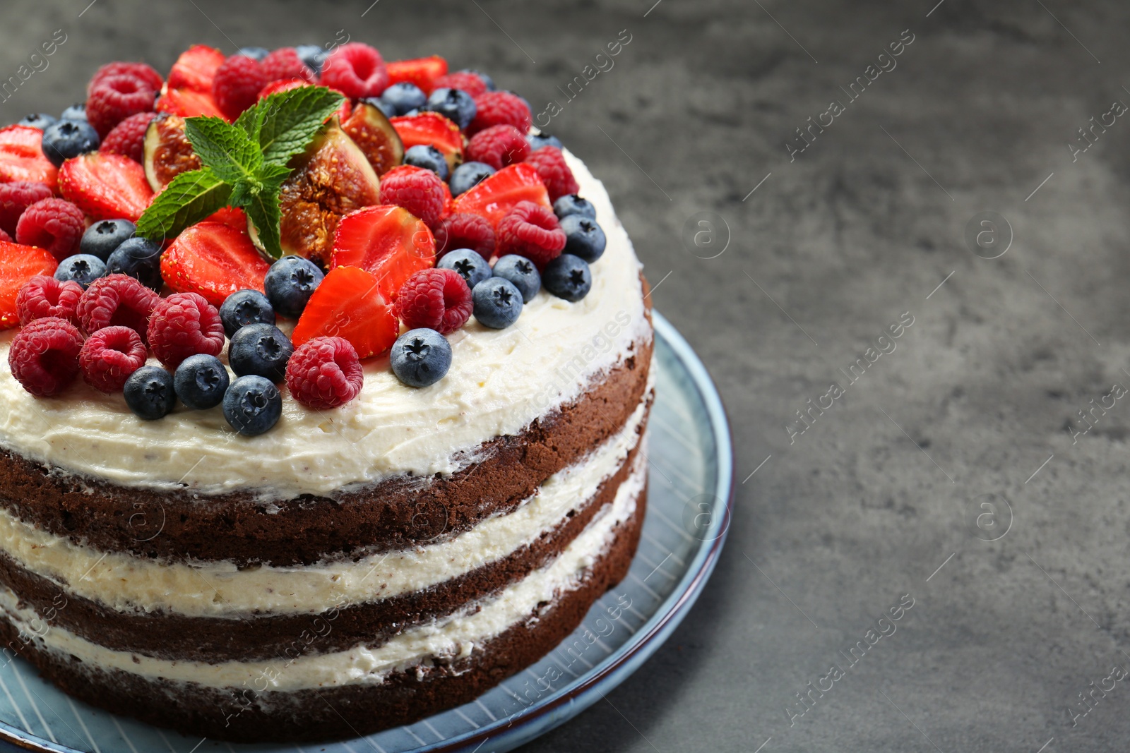 Photo of Delicious chocolate sponge cake with berries on grey table, closeup. Space for text