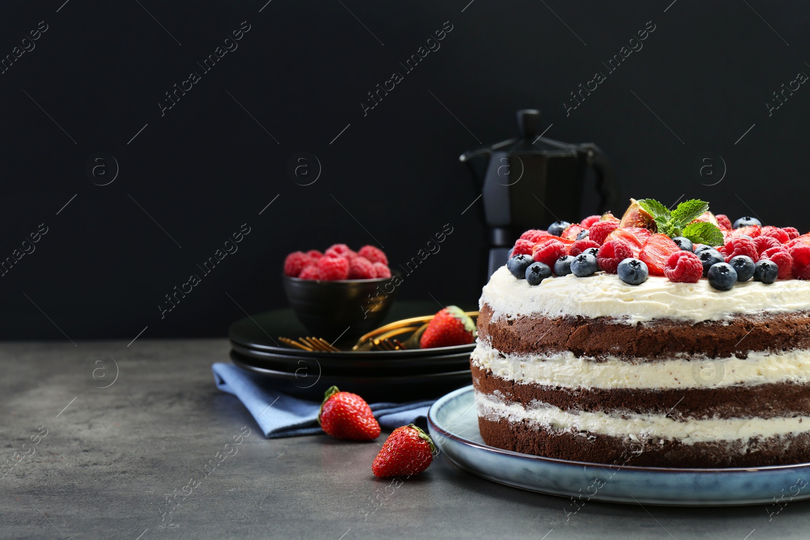 Photo of Delicious chocolate sponge cake with berries served on grey table. Space for text