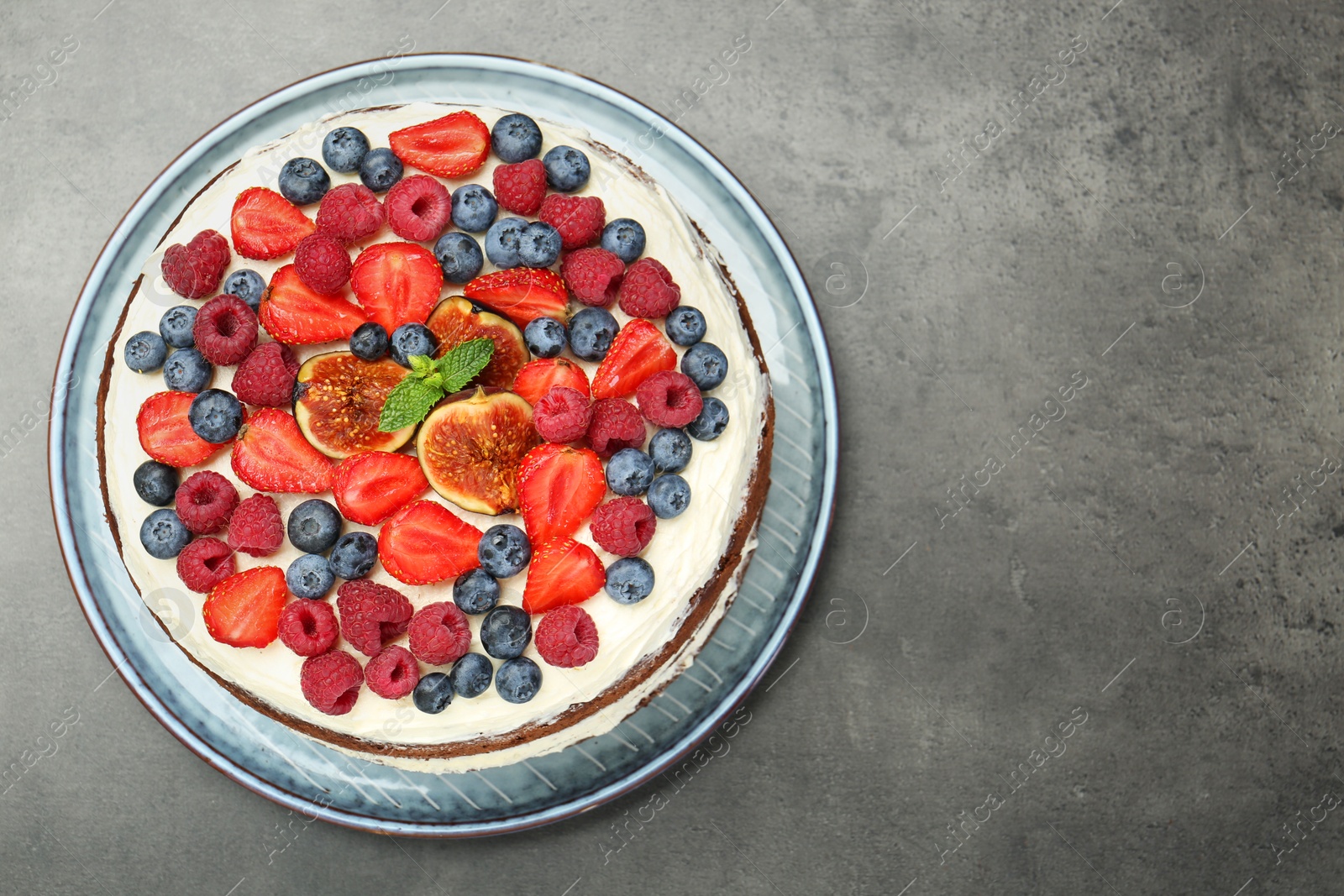 Photo of Delicious chocolate sponge cake with berries on grey table, top view. Space for text